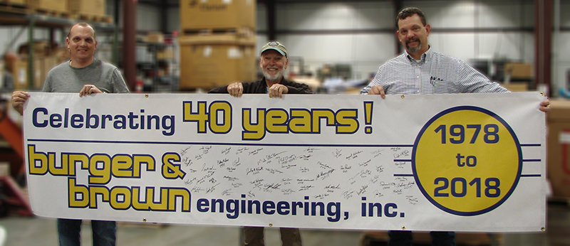 Corey Brown, Phil Burger and Mark Brown pose with our 40th Anniversary Banner at our celebration in March 2018.